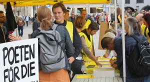 Reges Interesse am Unterschriftenlistentisch von Amnesty International. In den Vordergrund gehalten wird hier ein Schild mit der Aufschrift »Poeten für die Menschenrechte«. Foto: Jan-Eike Hornauer